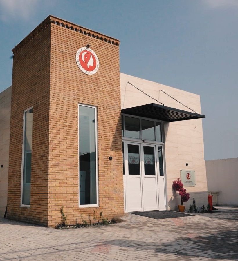 The Foundation's entrance in Sarfaraz Khan Village, with its logo on the brick tower